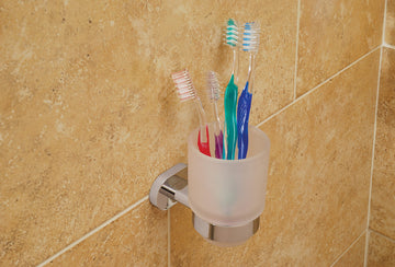 Frosted glass tumbler with chrome holder from Vado Life collection by Tuskan Tiles, resting on a bathroom countertop.